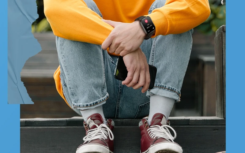 Homem sentado com o smartwatch Kumi KU6 no pulso.